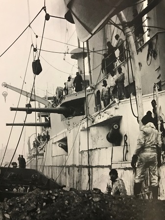 A naval crew works to load coal aboard ship